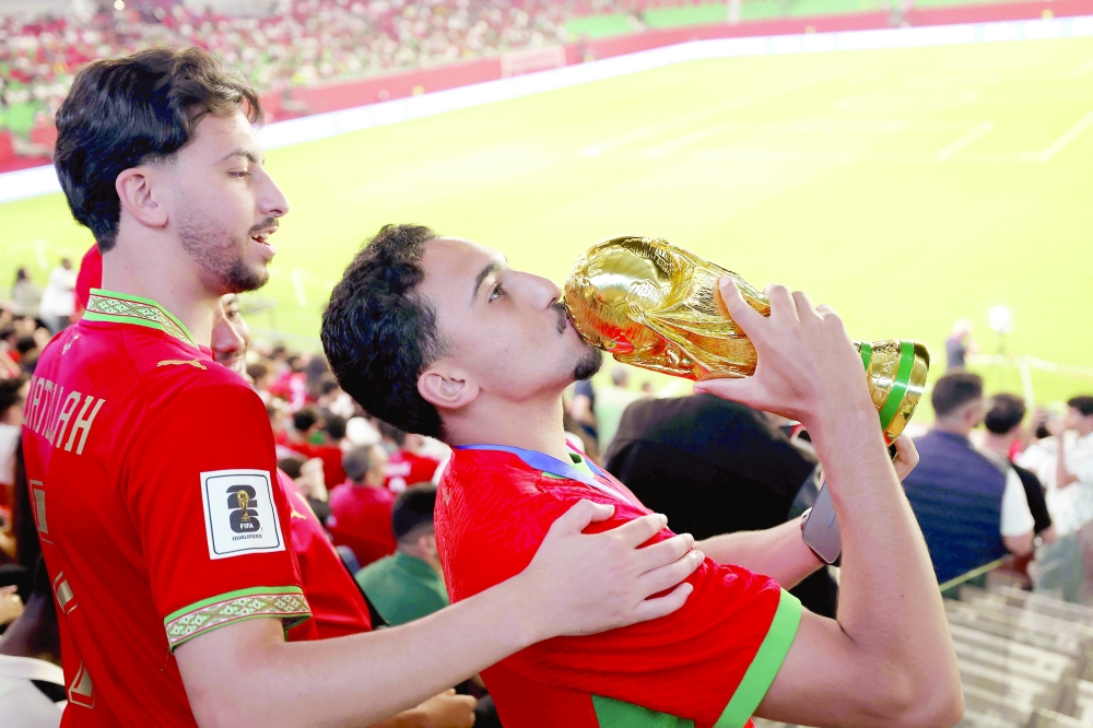 A Morocco fan kisses a replica of the trophy as he and others gather to watch the 2026 World Cup football tournament match between Brazil and Morocco on a giant screen at Moulay el-Hassan Stadium. — AFP