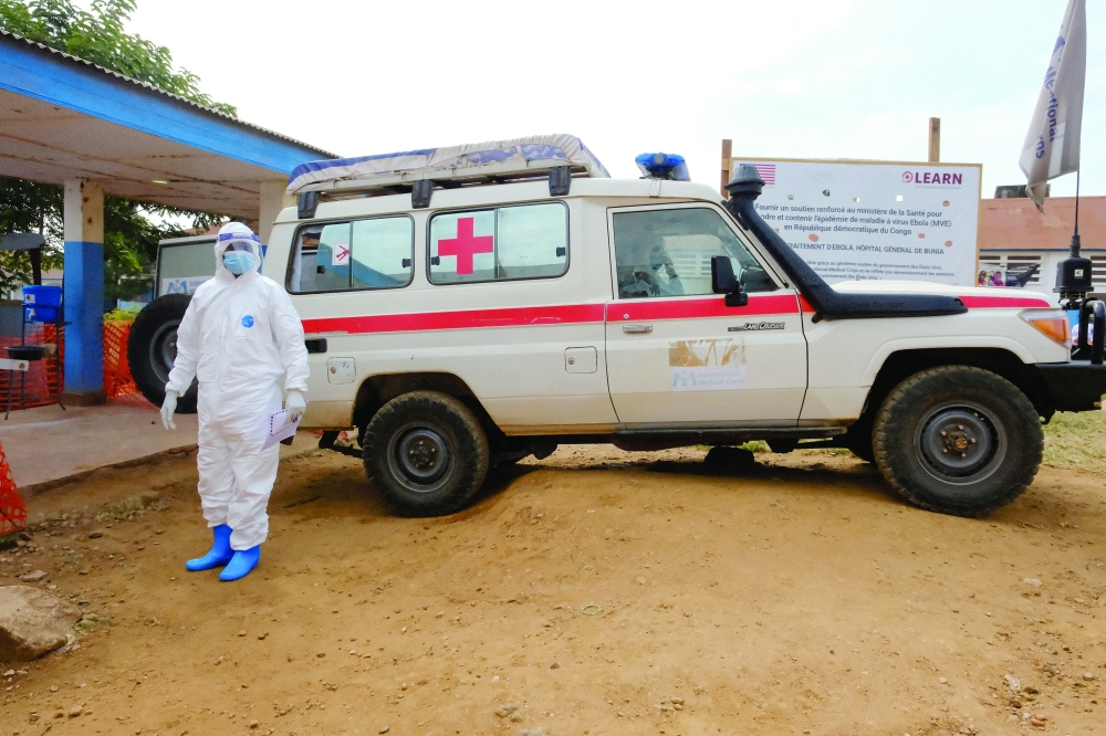 A doctor wearing personal protective equipment (PPE) stands near an ambulance at the Ebola Virus Disease Treatment Centre 