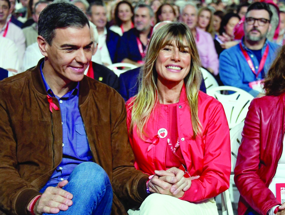 Spain's Prime Minister Pedro Sanchez (L) holds hands with his wife Begona Gomez. — AFP