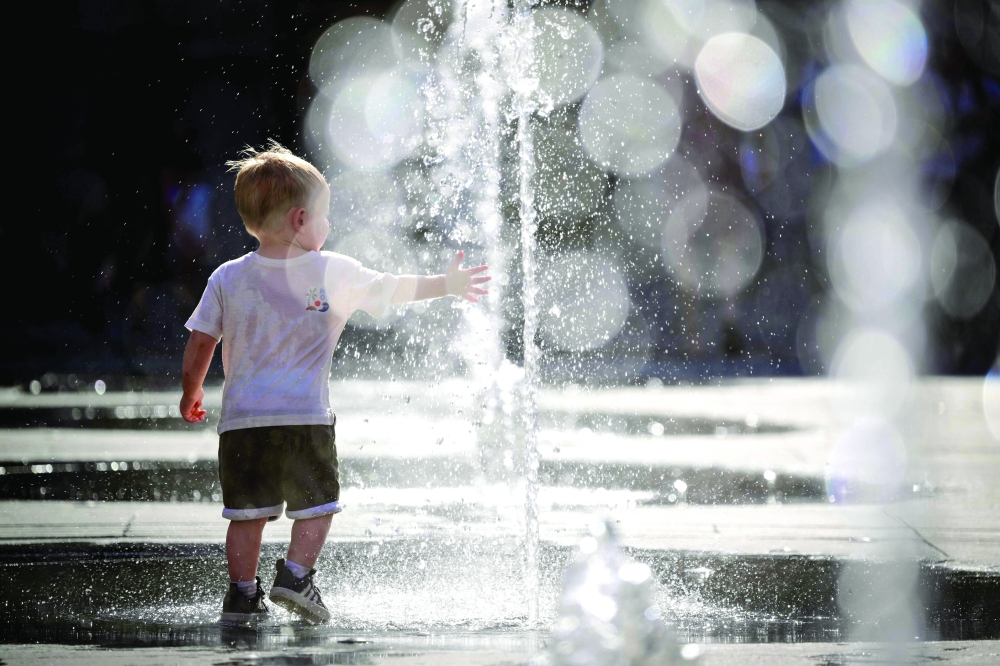A child plays in a fountain during a heatwave in Lyon, south-eastern France. — AFP