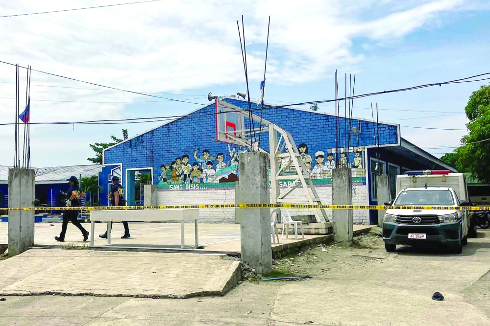 Police investigators walk in front of the school entrance after a shooting incident at a high school compound in Tacloban City, Leyte province on June 22, 2026. At least three teenaged students were killed and five others wounded on June 22, in a rare school shooting in the central Philippines, police said. (Photo by Noel  Sianosa / AFP)
