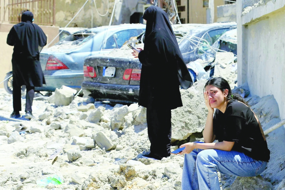 A Lebanese woman weeps as she sits on the rubble at the site of an Israeli air strike that targeted the southern Lebanese village of Qennarit. — AFP
