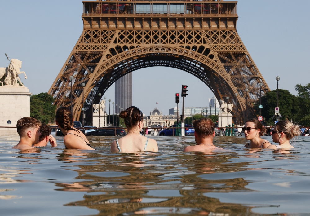 People cool off in the Trocadero Fountain next to the Eiffel Tower as temperatures rise during a heatwave affecting a large part of the country, in Paris, France