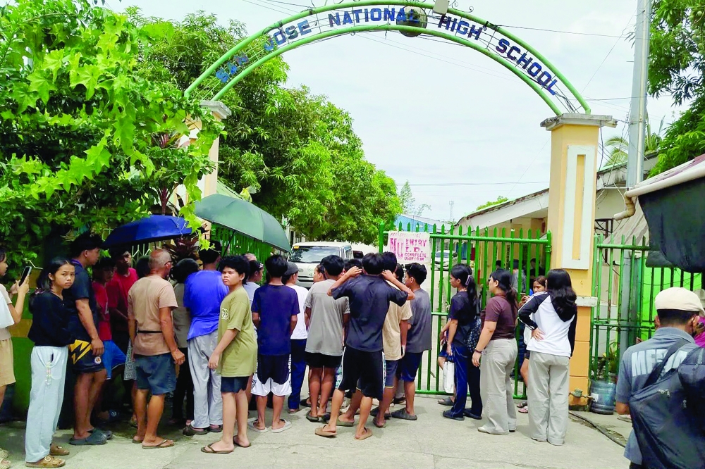 Students wait for permission to enter the school compound at the gate of San Jose High School in Tacloban City. — AFP