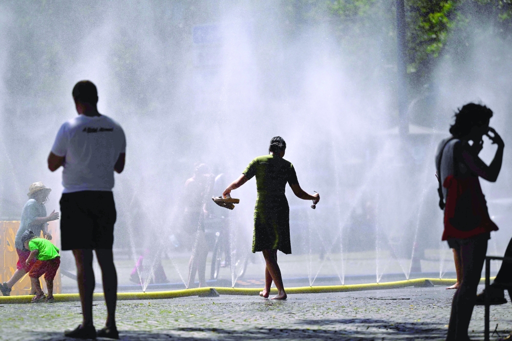 TOPSHOT - People stand near over water hoses spilling water to provide relief from the summer heat as part of Cologne’s climate adaptation measures in Cologne, western Germany on June 25, 2026 during a heatwave in Europe. A heatwave sweeping Europe was starting to peak in Germany on June 25, 2026, with several open-air events cancelled and temperatures expected to top 40C through the weekend. Large parts of the country are already under "severe to extreme heat stress" with temperatures soaring to around 37C, the German Weather Service (DWD) said.
 (Photo by Ina FASSBENDER / AFP)
