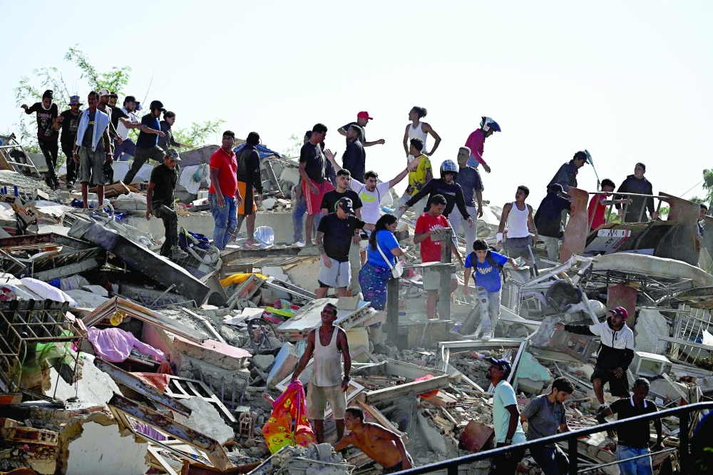 
People search for survivors while others try to salvage belongings in a collapsed building in Catia La Mar. — AFP 
