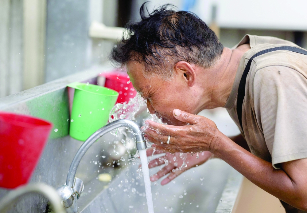 
An employee puts water on his face as he works in a greenhouse of tomatoes in Taule, western of France on Thursday. — AFP 