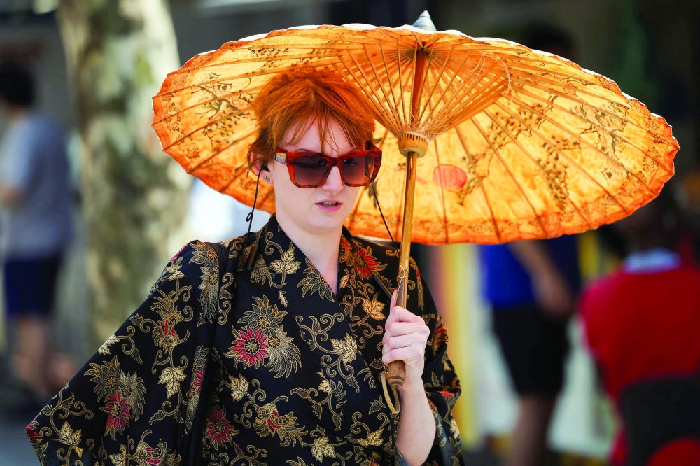 A woman shelters herself beneath an umbrella amid a heatwave in Manchester on Friday. — Reuters