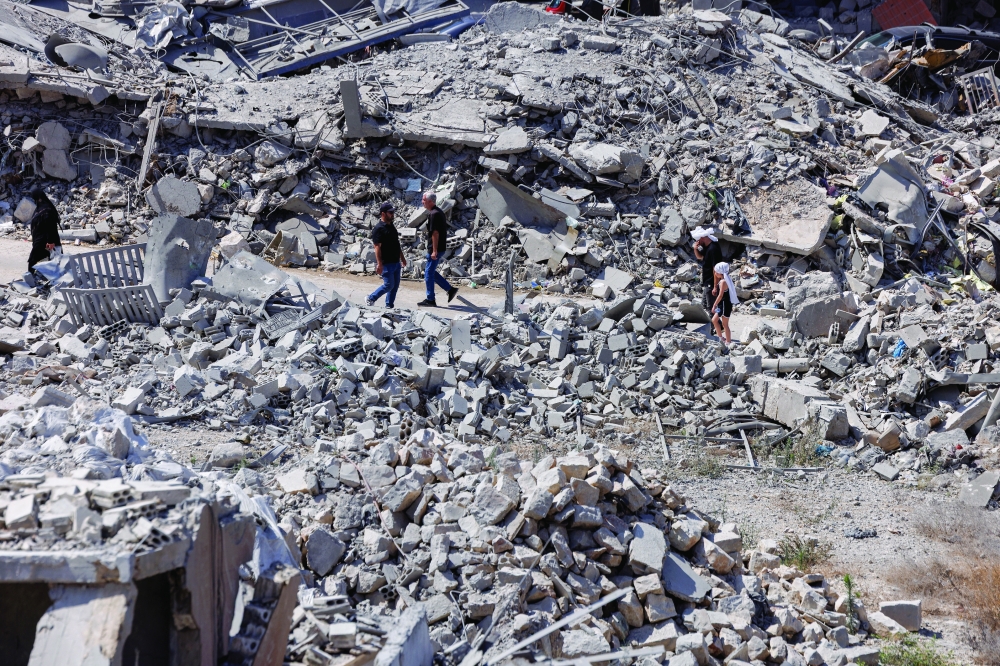 People walk past buildings destroyed by an Israeli airstrike in Nabatieh, southern Lebanon, on Friday. — Reuters
