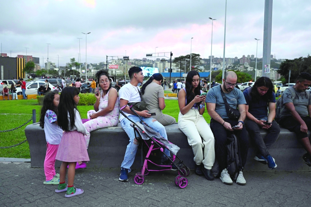 People use thier mobile phones as they remain in the street following an earthquake in Caracas. — AFP 