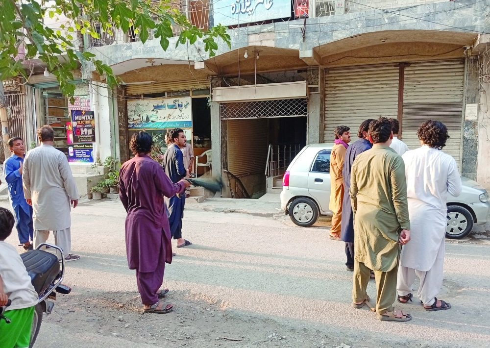 People stand in the street following an earthquake in Peshawar, Pakistan. — Reuters