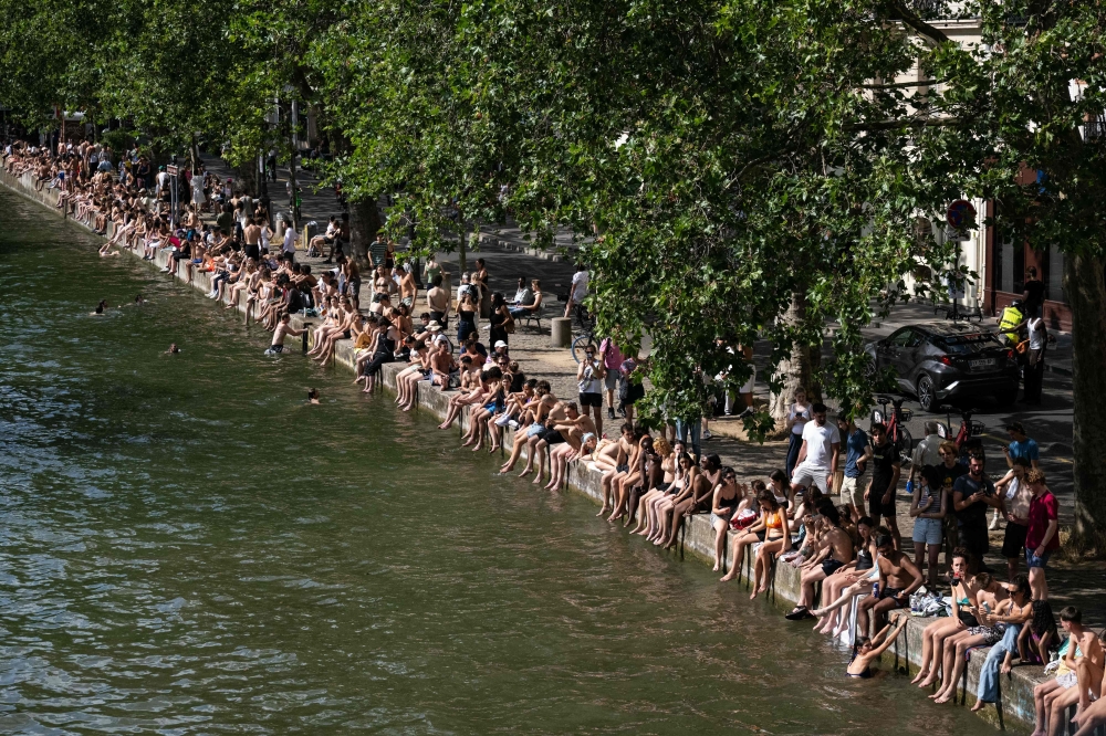 Swimmers sunbath on the banks of the Canal Saint-Martin as France experiences a heatwave in Paris on June 20, 2026.