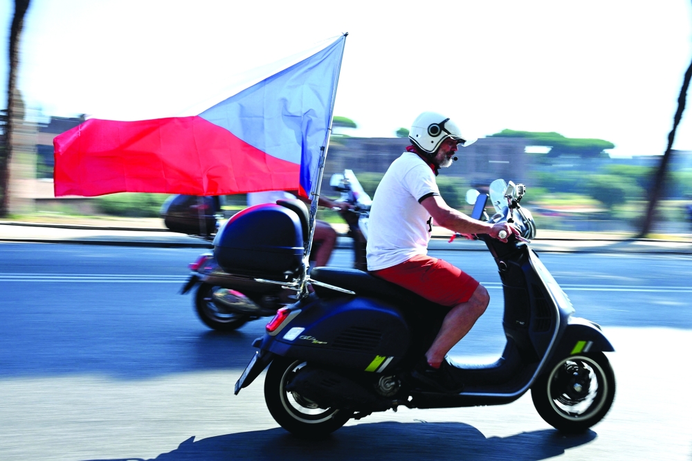 A Vespa enthusiast rides with a Czech Republic flag attached to his scooter during the parade of the Vespa World Days marking the 80th anniversary of the iconic Italian brand of scooters in Rome on June 27, 2026. (Photo by Alberto PIZZOLI / AFP)
