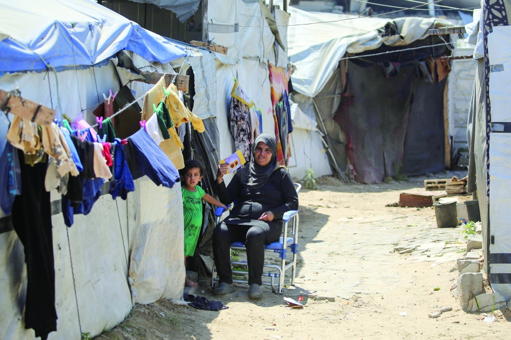 A Palestinian woman sits outside a makeshift shelter at a displacement camp in Nuseirat, in the central Gaza Strip, during a heatwave in the region on June 28, 2026. Gaza remains gripped by daily violence, with both the Israeli military and Hamas accusing one another of violating the truce in effect since October 10. The war flattened swathes of the territory, displaced most of the population at least once, and left hundreds of thousands of people living in tents and temporary shelters. (Photo by Eyad Baba / AFP)