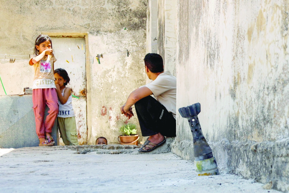 A man speaks with a child while sitting near an unexploded artillery shell that fell during reported overnight Israeli bombardment in Syria's southwestern Daraa province. — AFP