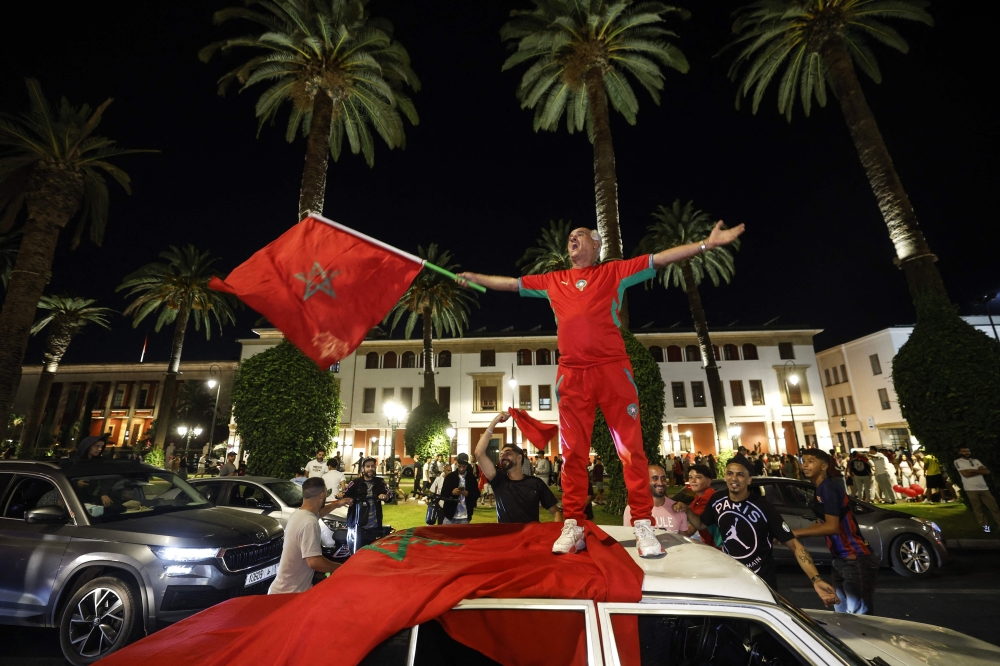 A man waves the Moroccan national flag as football fans celebrate Morocco's victory over the Netherlands in the Round of 32 of the 2026 World Cup, in Rabat  
