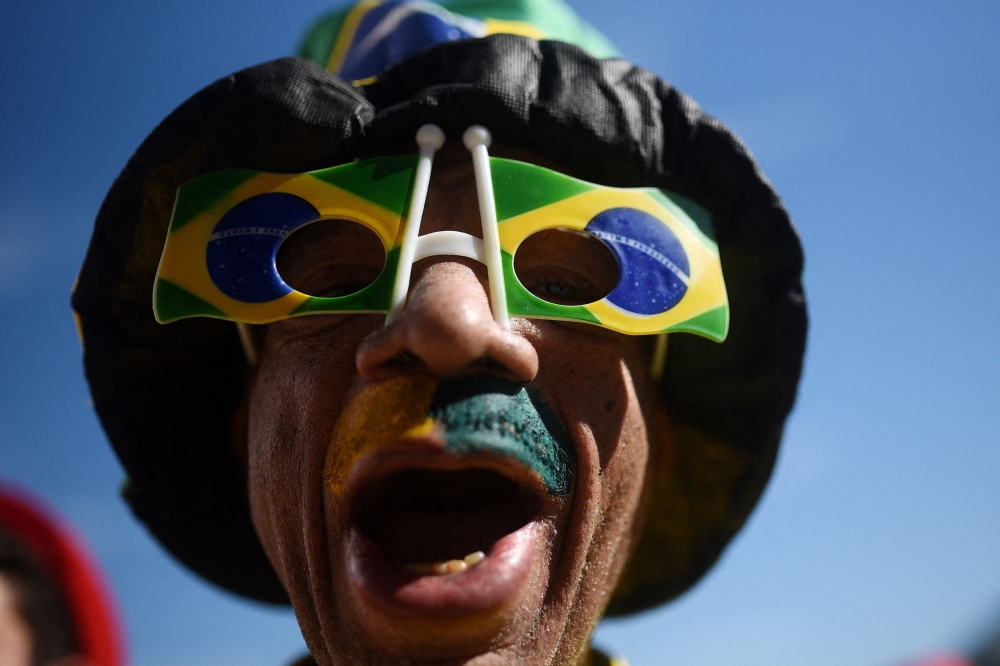   
A fan wears a Brazil themed hat and glasses at the fan zone  