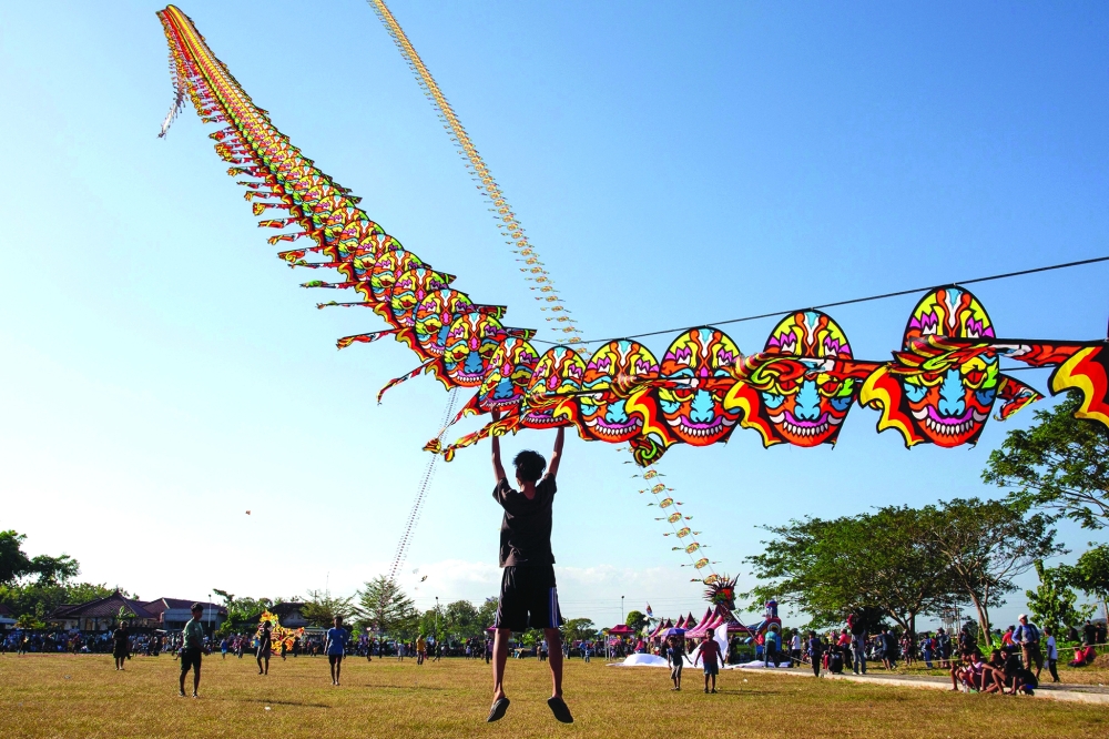 A participant is briefly lifted into the air as a giant dragon train kite catches the wind during a kite festival in Bantul, Indonesia. — AFP