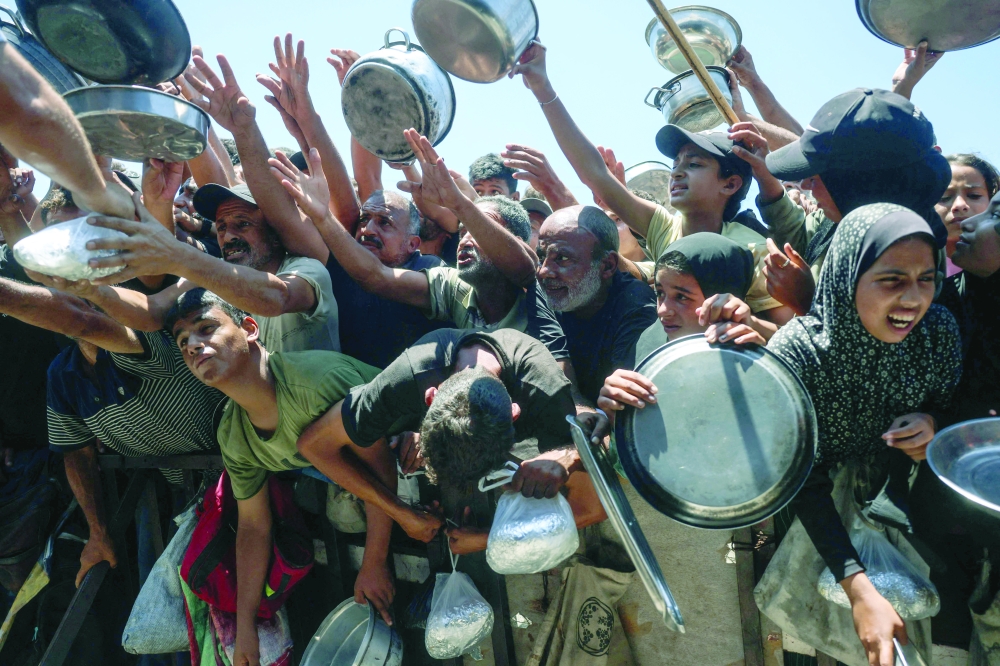 Displaced Palestinians gather to receive hot meals distributed by a charity kitchen in the Khan Yunis refugee camp in the southern Gaza Strip on June 29, 2026. Gaza remains gripped by daily violence, with both the Israeli military and Hamas accusing one another of violating the truce in effect since October 10. The war flattened swathes of the territory, displaced most of the population at least once, and left hundreds of thousands of people living in tents and temporary shelters. (Photo by Bashar Taleb / AFP)
