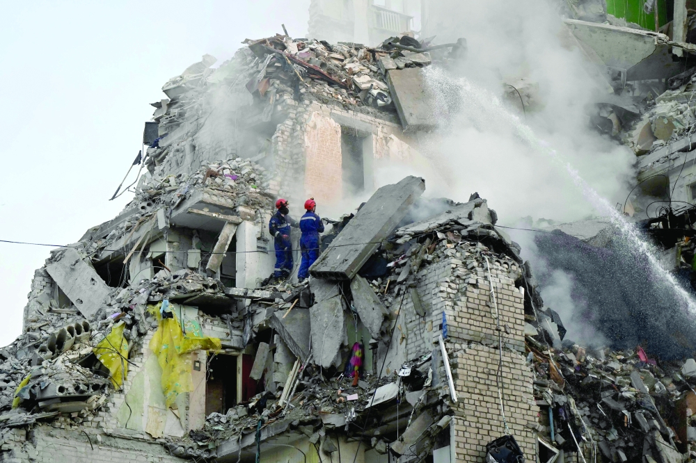 
Rescuers extinguish a fire and work in a damaged residential building in Kyiv on Thursday. — AFP 