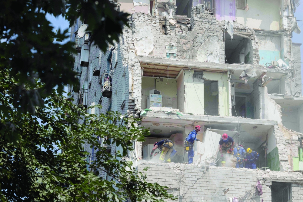 Rescue workers work in a residential building damaged following a Russian air attack on the Ukrainian capital of Kyiv amid the Russian war in Ukraine. - AFP