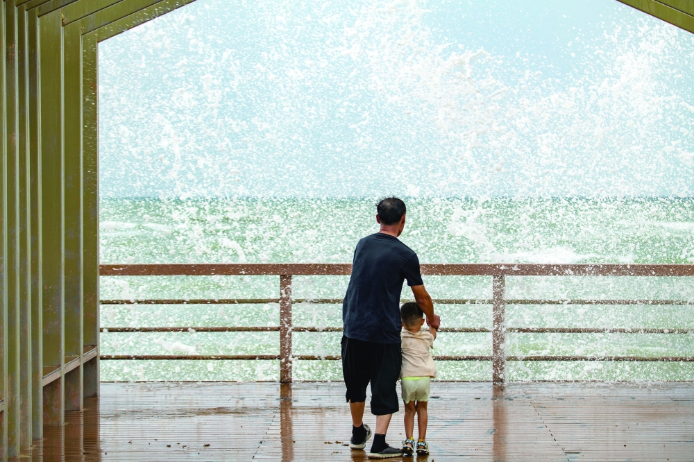 People watch waves crashing against the shore as Tropical Storm Maysak approaches in Boao, Qionghai, Hainan province, China. - Reuters