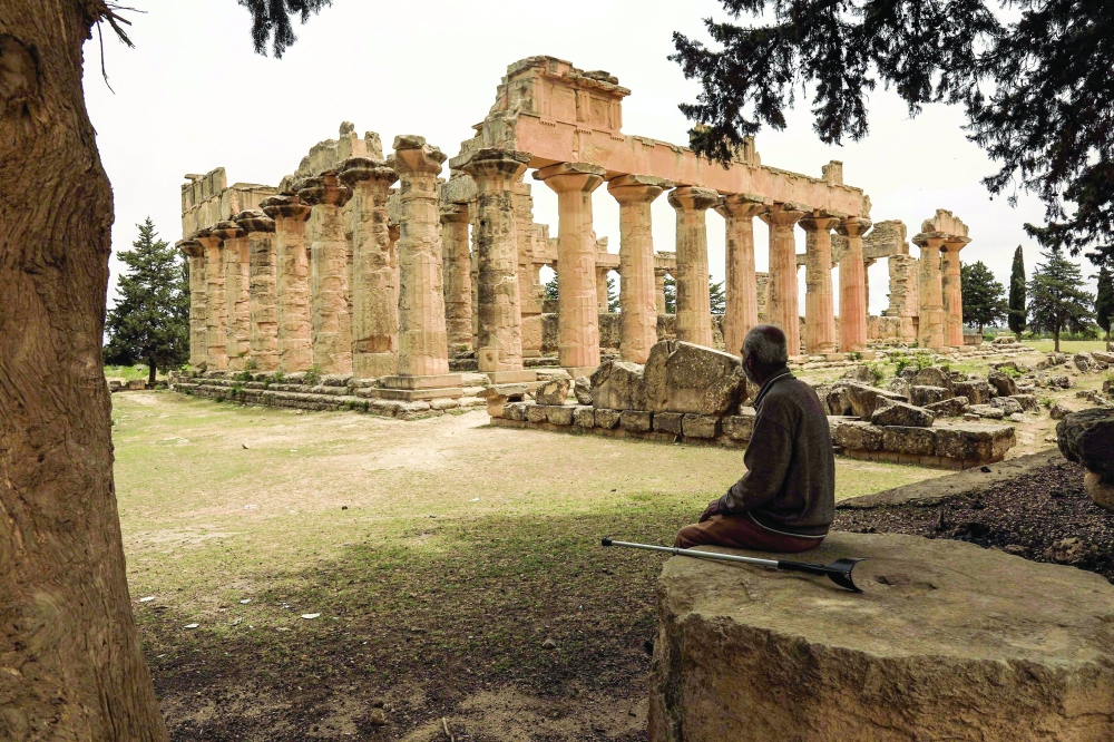 A man sits in the shade in front of the Temple of Zeus at the archaeological site of Cyrene. — AFP