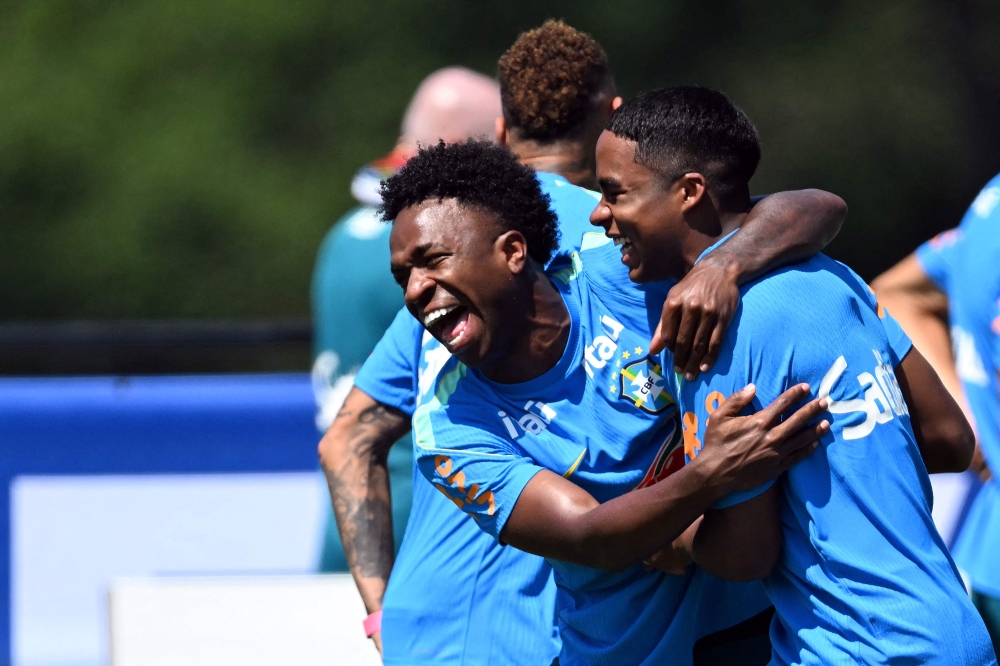 Brazil's forward #07 Vinicius Junior (L) and Brazil's forward #19 Endrick share a laugh during a training session  