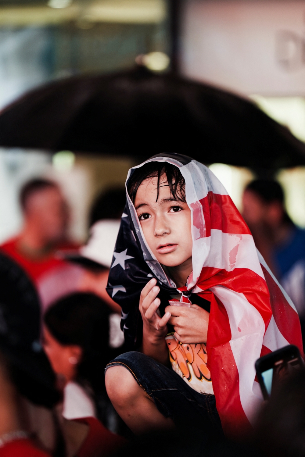 A boy covers himself with a U.S. flag as he watches World Cup fans celebrate, in Times Square in the Manhattan borough of New York, U.S., July 4, 2026. REUTERS/Bing Guan