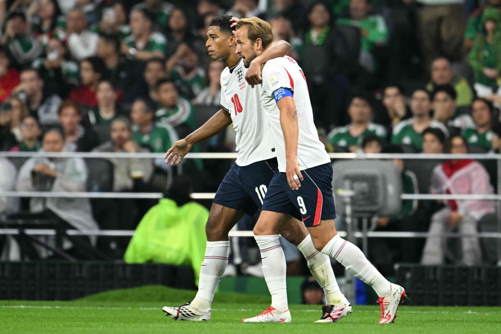  England's midfielder #10 Jude Bellingham (L) celebrates scoring his team's first goal with teammate forward #09 Harry Kane (R)  