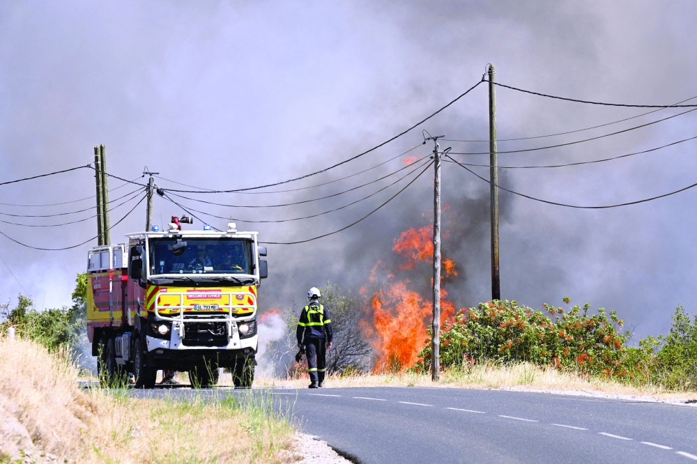 A French Civil Security firefighter walks on a road next to a wildfire near Ille-sur-Têt, southern France. — AFP