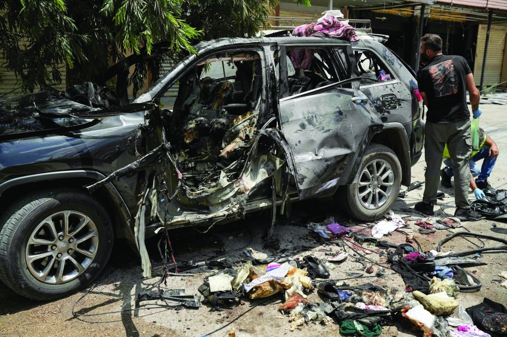 First responders inspect the wreckage of a car reportedly targeted by an Israeli strike in Nabatieh. — AFP