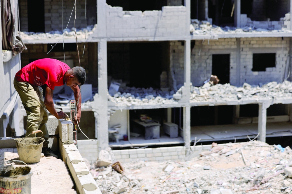 A bricklayer restores the balcony of a building destroyed in an Israeli air strike in Tyre, southern Lebanon. — Reuters