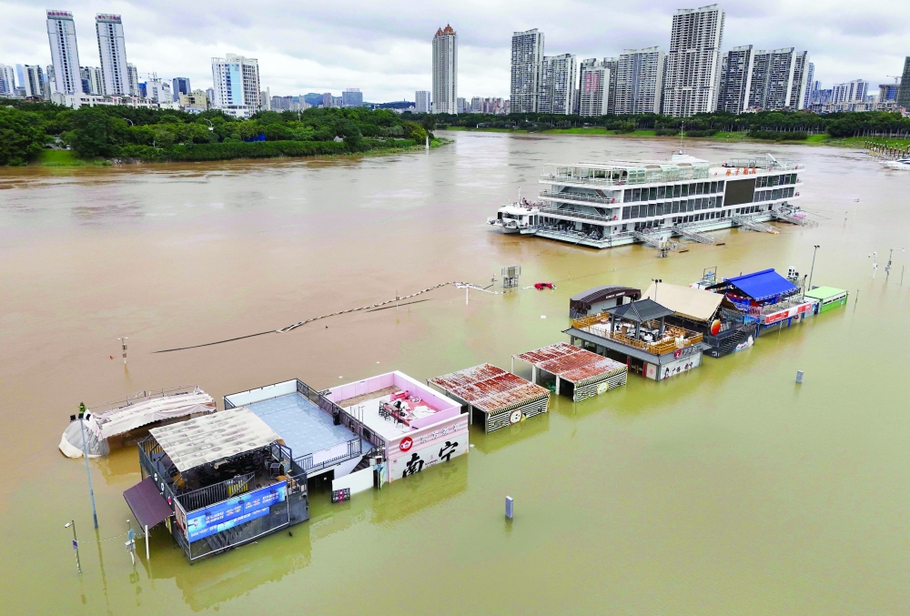 Flooded shops along a submerged riverside walk are seen by the overflowing Yongjiang river in Nanning, in China’s southern Guangxi region on July 7, 2026. The death toll from devastating storms in parts of China rose to 15 on July 7, with hundreds more injured and tens of thousands evacuated, state media reported, as President Xi Jinping urged "all out" rescue efforts.

