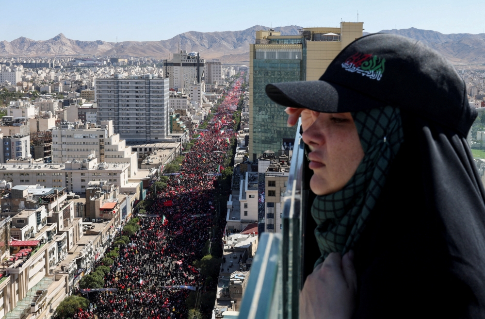 A woman looks on, as mourners gather on the day of the burial of Iran's late Supreme Leader Ayatollah Ali Khamenei  in Mashhad, Iran