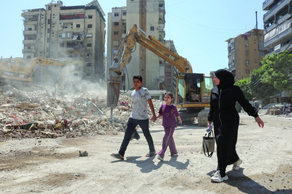 People walk past the rubble of buildings damaged in Israeli strikes in Beirut’s southern suburbs, following a ceasefire agreement between Lebanon and Israel, in Beirut. - Reuters