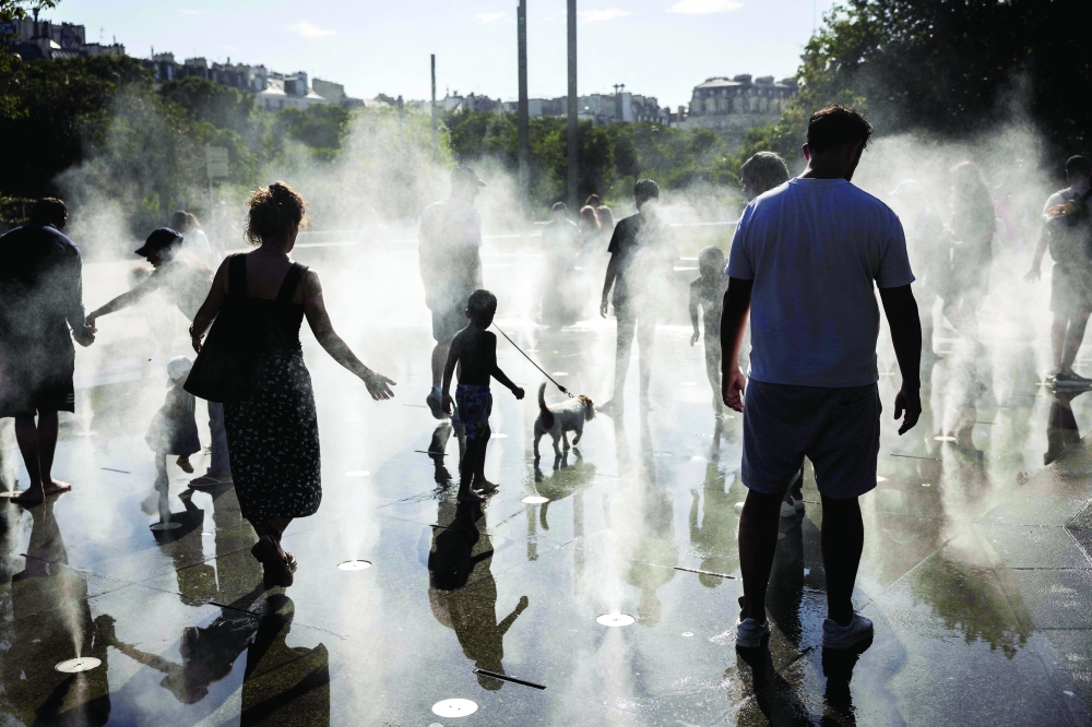 Children play in a splash pad during a heatwave in Paris. — AFP