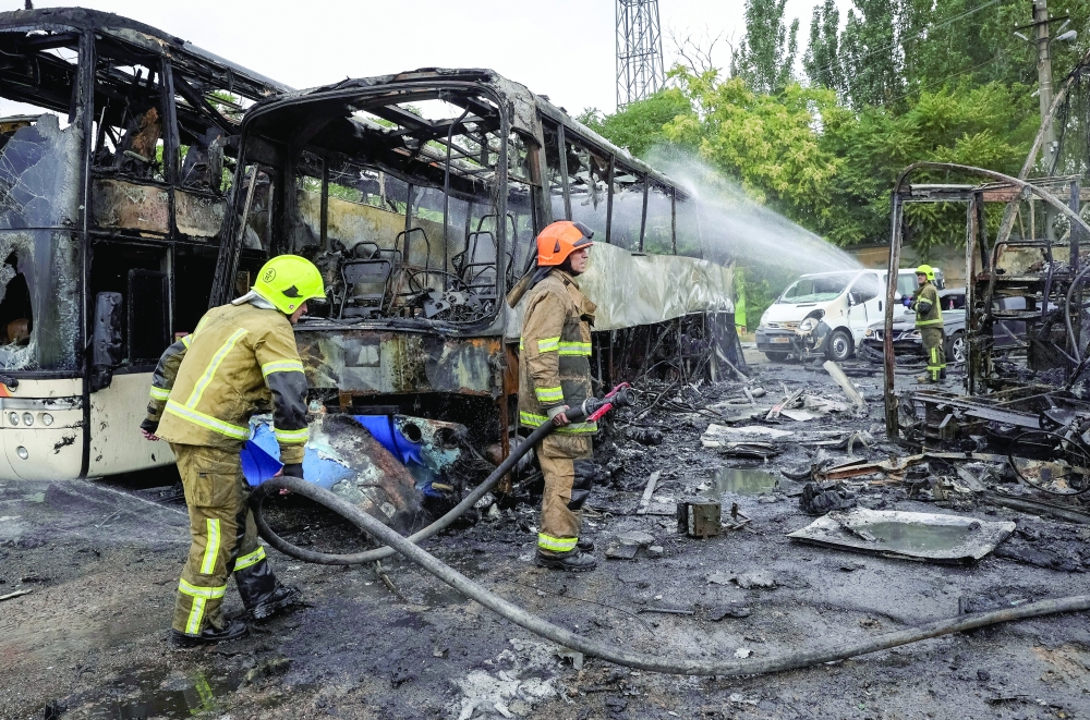 Firefighters work at the site of a bus parking hit by a Russian drone strike in Odesa. — AFP