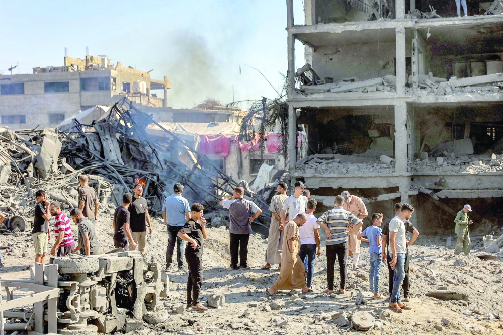 People gather by the rubble of destroyed buildings following an Israeli strike on an industrial area in Gaza City on July 12, 2026. Gaza's civil defence and hospitals said an Israeli drone strike and gunfire killed five people and injured several others on July 12. A ceasefire remains in place between Israel and Hamas, but it has not halted violence in Gaza, and efforts to secure a lasting agreement to end the war have stalled.