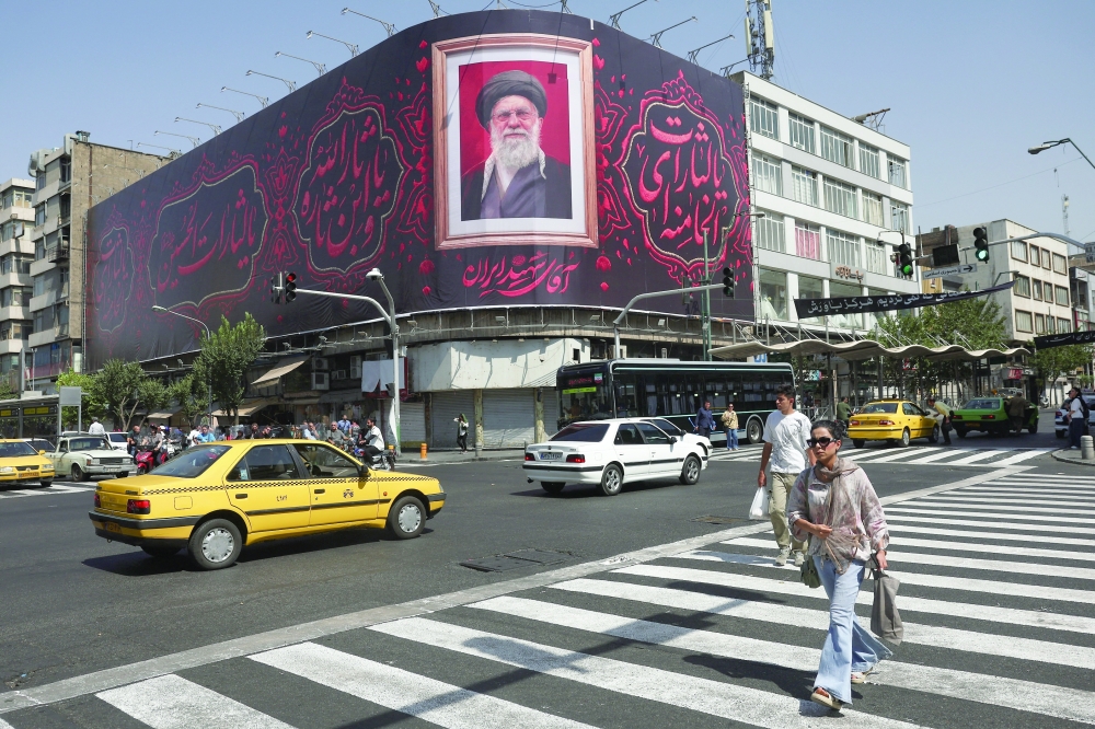People walk past a billboard with an image of Iran's late Supreme Leader Ayatollah Ali Khamenei in Tehran. — Reuters