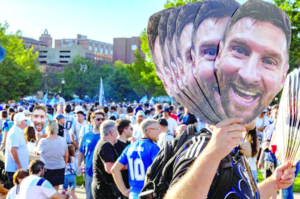 An Argentine fan holds cardboard cutouts depicting Argentina's Messi. — AFP 