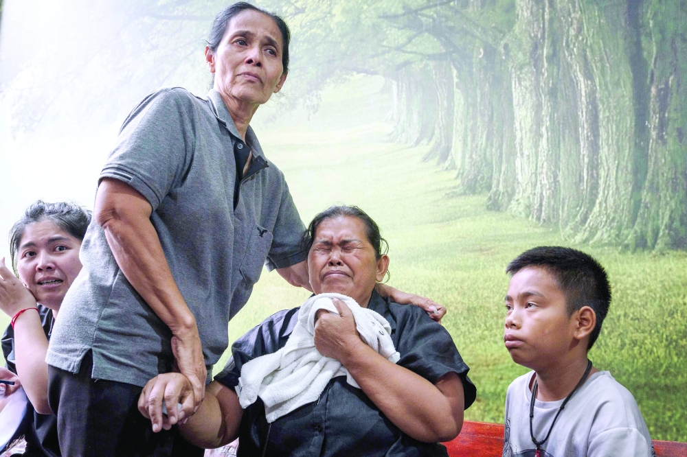 Relatives mourn victims killed in a club fire at the Police General Hospital in Bangkok. — AFP
