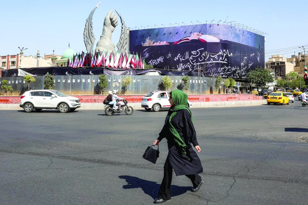 A woman crosses Tehran's Enghelab Square on Wednesday, past a giant anti-US billboard. — AFP
