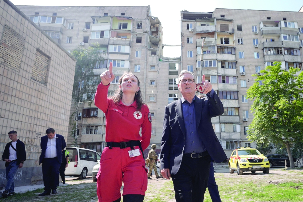 Britain's Prime Minister Keir Starmer (R) meets emergency responders in Kyiv, where a building in the background was hit by a Russian missile on July 6, as part of Starmer's last visit to Ukraine before leaving office on Thursday. — Reuters