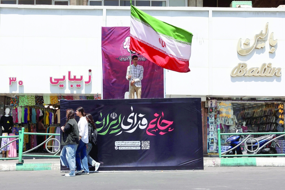 An Iranian man holds Iran’s national flag at Valiasr Square in Tehran on Thursday. — AFP