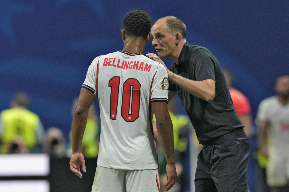 England's German head coach Thomas Tuchel (R) gives instructions to England's midfielder #10 Jude Bellingham (L) on the touchline  