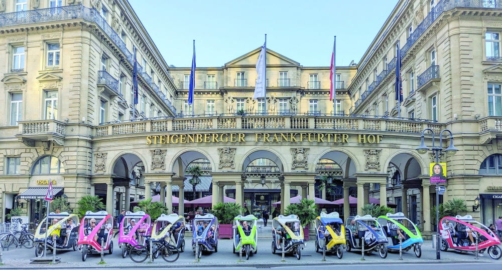 Velotaxis lined up before the landmark Belle Époque-style luxury hotel