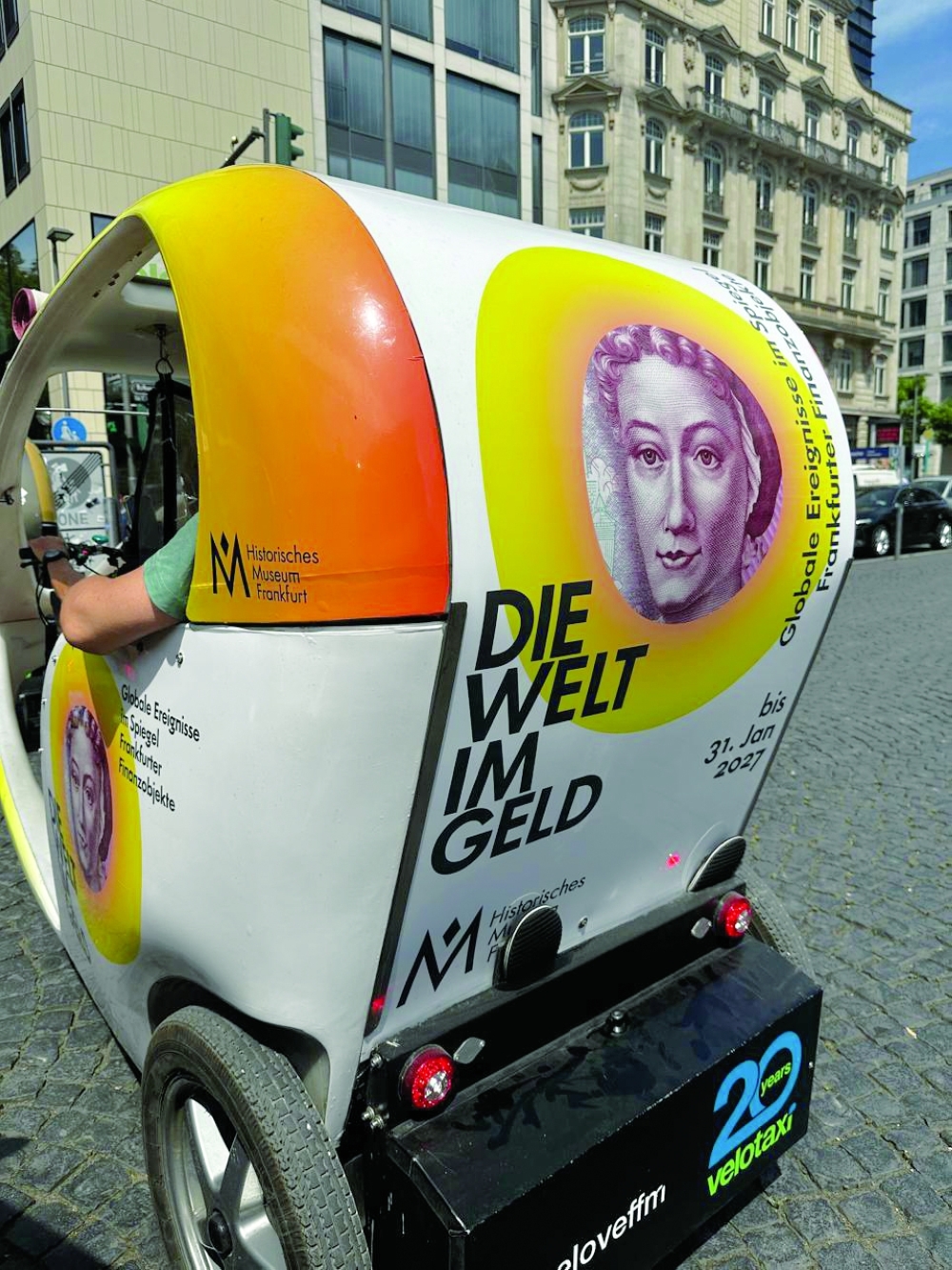 “A colourful Velotaxi with eye-catching advertisements on the streets of Frankfurt