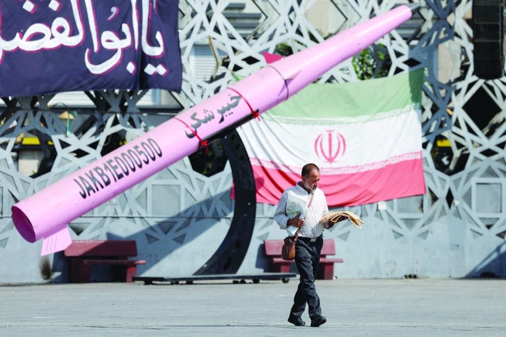 A man walks next to a symbolic mockup of an Iranian missile and an Iranian flag at Imam Hussein Square in Tehran. — AFP