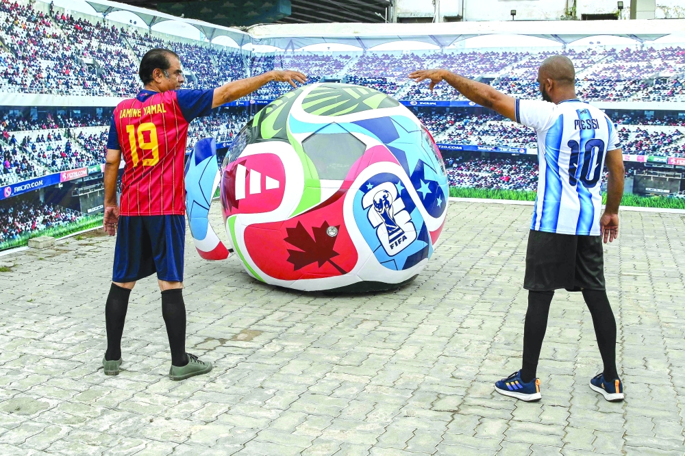 Fans in Yamal and Messi jerseys pose beside a World Cup-themed car. —  AFP